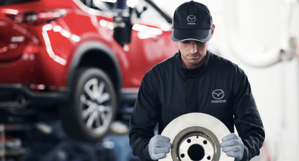 A Mazda service technician handles new brakes in the service center he's working in. Schedule service with Mazda of Spartanburg today.