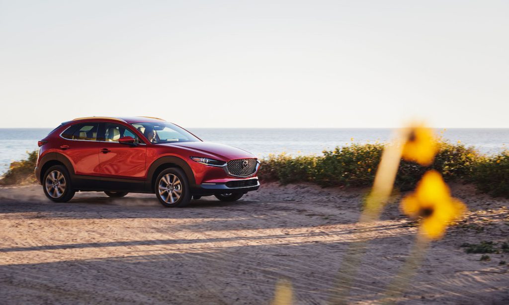 A red Mazda CX-30 SUV driving on the beach sand during sunset. With a powerful engine, off-road capability is a standard feature in your new Mazda in Spartanburg.