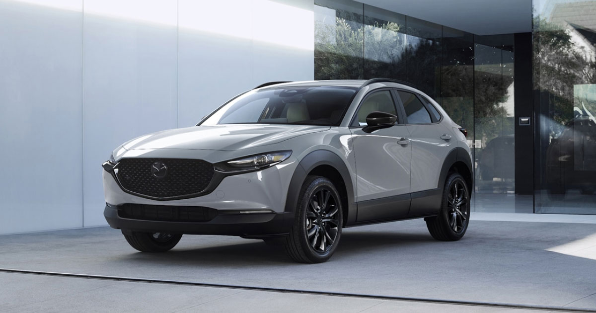 A silver Mazda CX-30 parked in front of a building during the day.