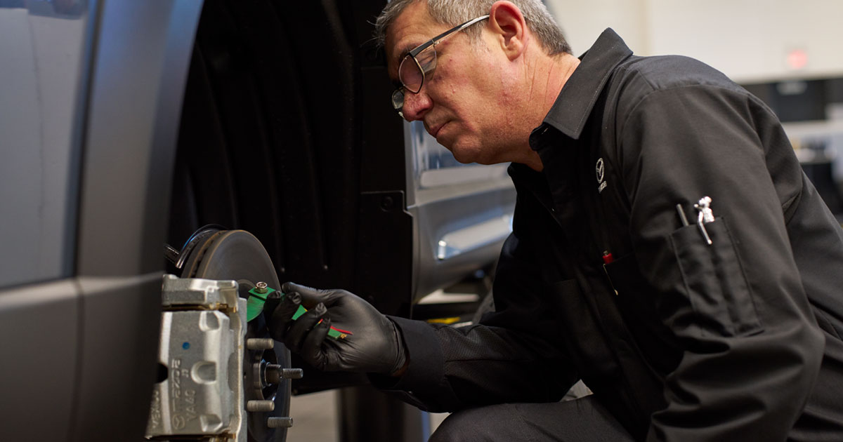 A service technician replacing a vehicle's brake pad.