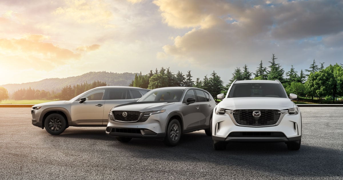 3 Mazda SUVs sit lined up side by side with a sunset in the background